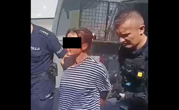 Policjanci prowadzą zatrzymaną kobietę.