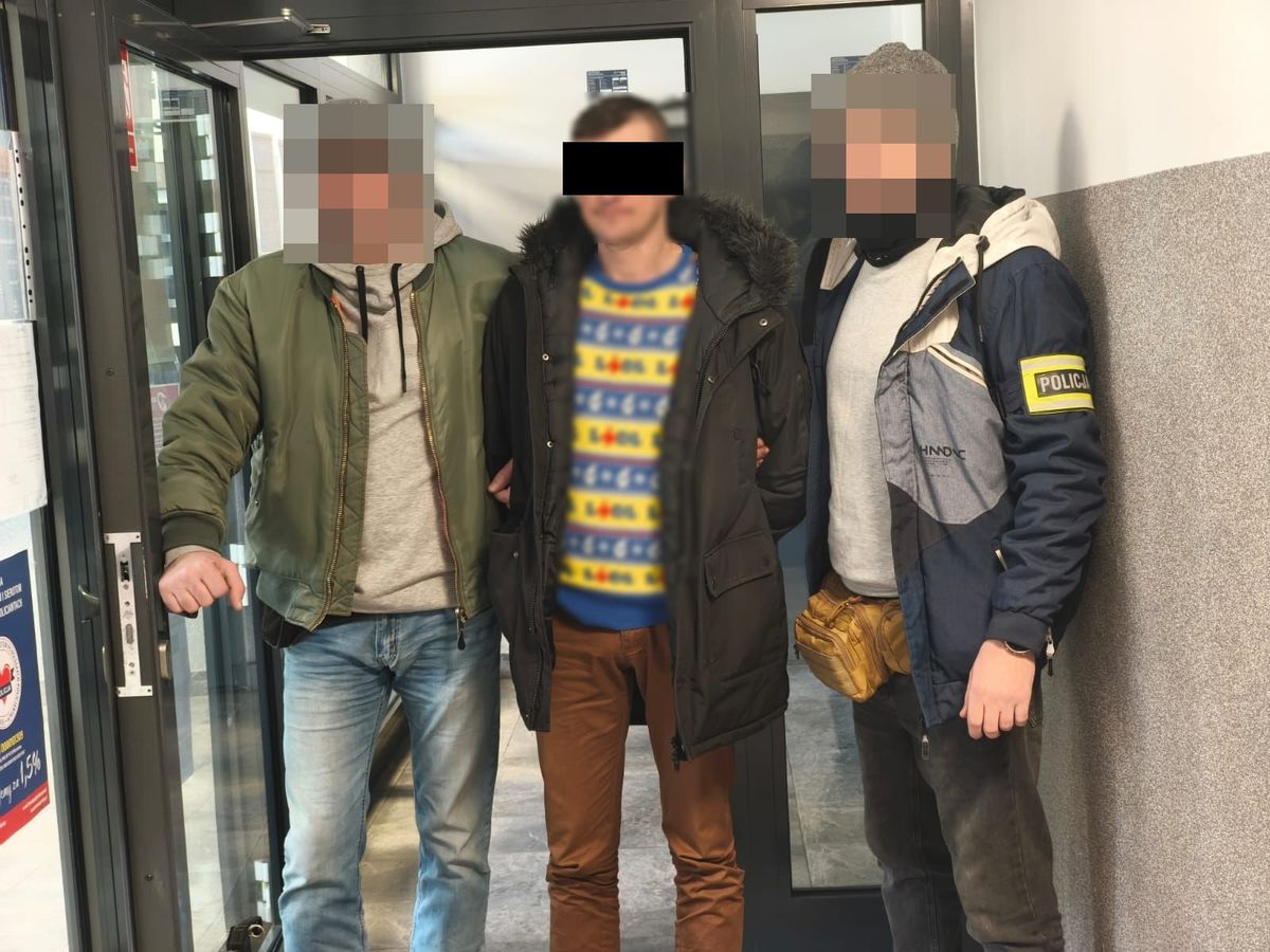 Policjanci prowadzą zatrzymanego mężczyznę.