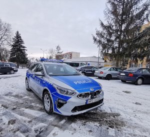 policyjny radiowóz stoi na parkingu, w tle widać inne pojazdy