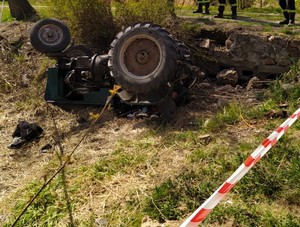 w rowie leży wywrócony do góry kołami ciągnik rolniczy. teren odgrodzony policyjną taśmą