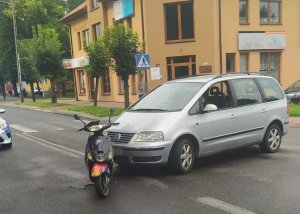 na skrzyżowaniu stoi srebrne auto. przód samochodu styka się z tyłem stojącego obok motoroweru.