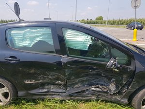 czarne auto stoi na poboczu. widoczne wgniecenia i zarysowania oraz rozłożone kurtyny powietrzne z prawej strony samochodu.