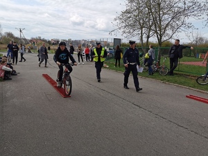 policjanci patrzą na chłopca, który na rowerze pokonuje tor przeszkód