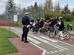 policjant stoi przed młodzieżą na rowerach