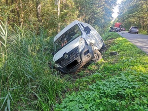 na poboczu w rowie stoi pochylony biały samochód renault z rozbitym przodem. za nim w oddali widać stojący na jezdni szary rozbity samochód