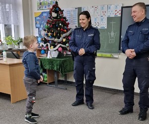 policjanci rozmawiają z chłopcem. w tle widać choinkę