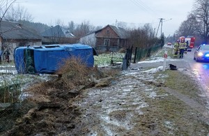 na posesji na boku leży niebieski bus. w oddali widać samochód policyjny.