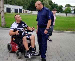 mężczyzna na wózku inwalidzkim stojący z policjantem