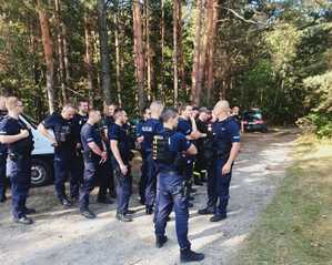 grupa policjantów pod lasem podczas poszukiwań