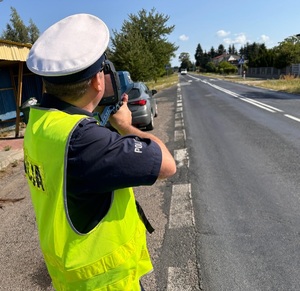 policjant dokonujący pomiaru prędkości przy użyciu ręcznego miernika prędkości