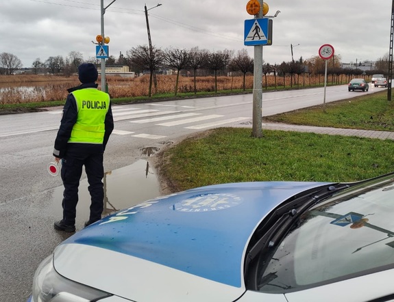 policjant trzymający w ręku tarczę do zatrzymywania pojazdów