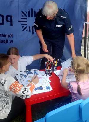 policjantka daje dziecku element odblaskowy