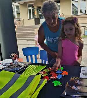 policjantka daje dziecku element odblaskowy
