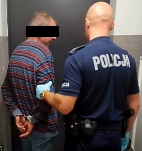 zatrzymany mężczyzna trzymany przez policjanta