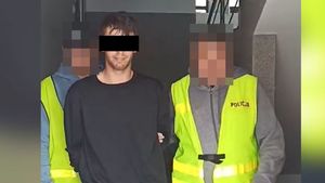 Policjanci prowadzą zatrzymanego mężczyznę.