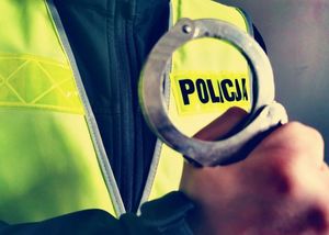 policjant w kamizelce odblaskowej trzyma w ręku kajdanki