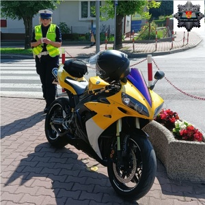 policjantka stojąca przy motocyklu koloru żółtego