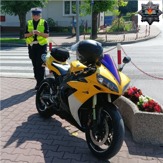 policjantka stojąca przy motocyklu koloru żółtego