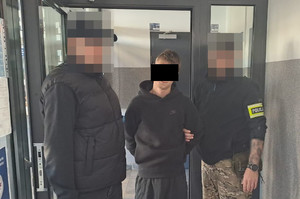 Policjanci prowadzą zatrzymanego mężczyznę.