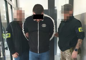 Policjanci prowadzą zatrzymanego mężczyznę.