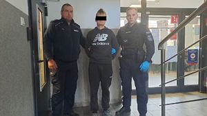 Policjanci prowadzą zatrzymanego mężczyznę.