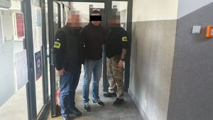 Policjanci prowadzą zatrzymanego mężczyznę.
