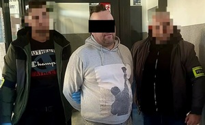 mężczyzna z zasłoniętymi oczami stojący z policjantami