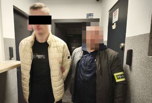 Policjant prowadzi zatrzymanego mężczyznę.