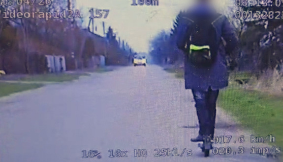 Kadr z wideorejestratora na którym widać nietrzeźwego mężczyznę jadącego na hulajnodze.