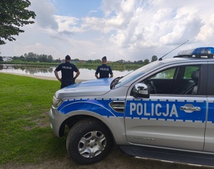 policjanci przy radiowozie a w tle widoczne kąpielisko