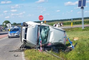 samochód w kolorze srebrny metalik leży w rowie. Przednia szyba samochodu jest stłuczona od wewnątrz. w dalszym planie policyjny radiowóz